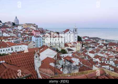 View of terracotta roofs and the ancient dome from Miradouro Alfama viewpoint at dusk Lisbon Portugal Europe Stock Photo