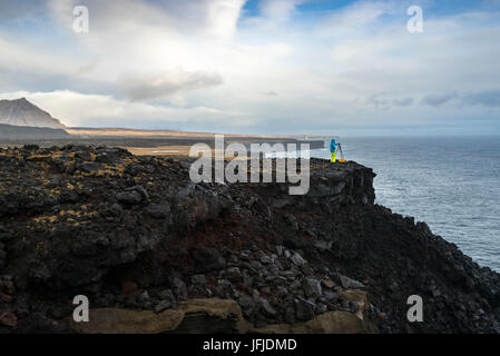 A photographer is taking pictures with tripod standing on the cliffs near Londrangar, Snaefellsjoekull National Park, Western Iceland, Europe Stock Photo