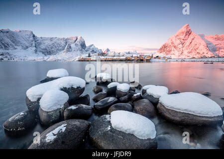 The colors of dawn frames the fishermen houses surrounded by frozen sea Sakrisøy Reine Nordland Lofoten Islands Norway Europe Stock Photo