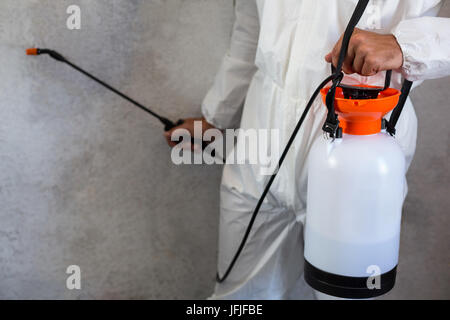 Midsection of manual worker using spray on wall Stock Photo