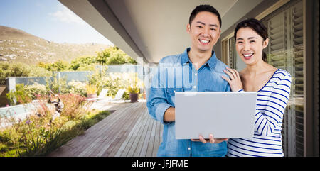 Composite image of portrait of couple using laptop Stock Photo