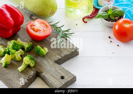 Fresh vegetables - zucchini, tomatoes, sweet pepper, broccoli, olive oil and spices on a wooden cutting board, copy space. Stock Photo