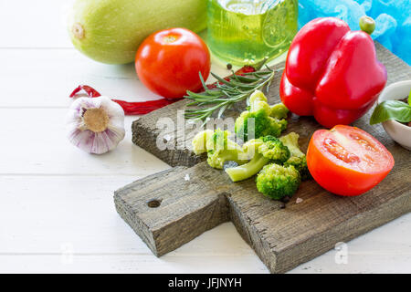 Fresh vegetables - zucchini, tomatoes, sweet pepper, broccoli, olive oil and spices on a wooden cutting board, copy space. Stock Photo