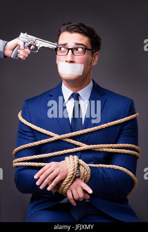 Businessman taken hostage and tied up with rope Stock Photo