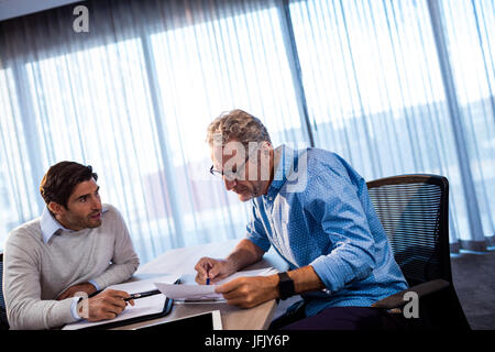 Two businessmen reading a document and interacting Stock Photo