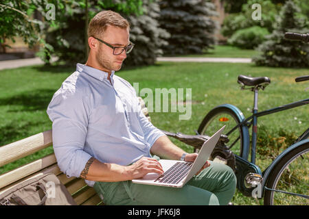Closeup of businessman hands typing on laptop while coffee breaks in park Stock Photo