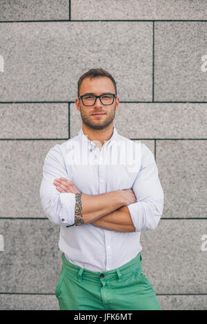 Cool young bearded hipster man wearing shirt, keeping arms crossed Stock Photo