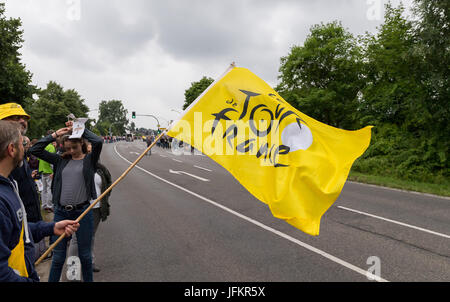 Korschenbroich, Germany. 02nd July, 2017. Fan holding a yellow Tour de France flag standing on the sidewalk and await for the arrival of the peloton in Korschenbroich, Germany, during the Dusseldorf-Luttich stretch, the 2nd stage of the Tour de France, part of the UCI World Tour, 02 July 2017. Photo: Guido Kirchner/dpa/Alamy Live News Stock Photo