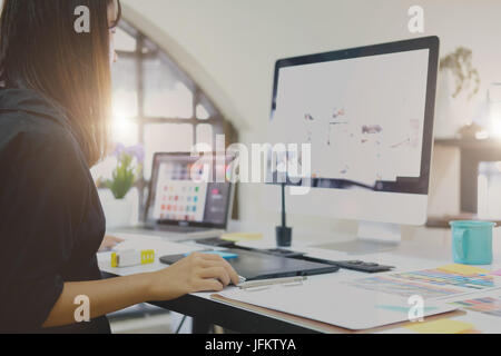 Young asian graphic designer working on computer using digital tablet at office. Stock Photo