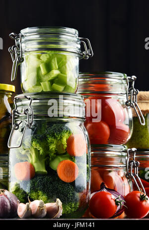 Jars with marinated food and organic raw vegetables. Stock Photo