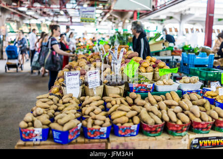 Montreal, Canada - May 28, 2017: Man selling produce by stands at Jean-Talon farmers market with displays Stock Photo