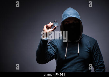 Hacker wearing hood in dark room Stock Photo