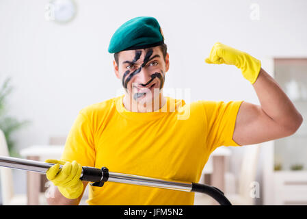 Funny man in military style cleaning the house Stock Photo