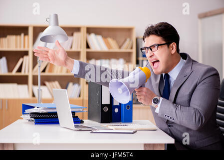 Businessman with loudspeaker megaphone in office Stock Photo