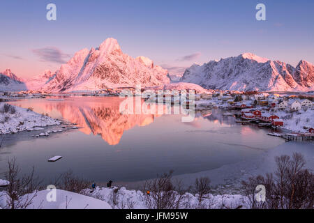 Snowy peaks are reflected in the frozen Lake Jaegervatnet at sunset ...