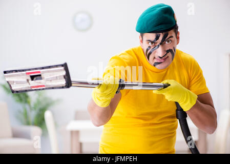 Funny man in military style cleaning the house Stock Photo