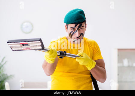 Funny man in military style cleaning the house Stock Photo