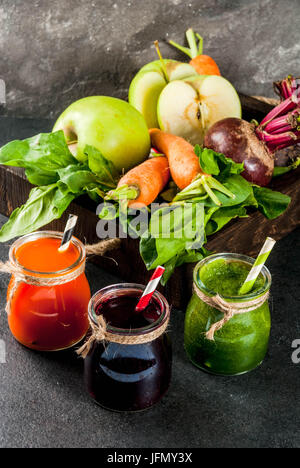 Vegan diet food. Detox drinks. Freshly squeezed juices and smoothies from vegetables: beets, carrots, spinach, cucumber, apple. On dark stone backgrou Stock Photo