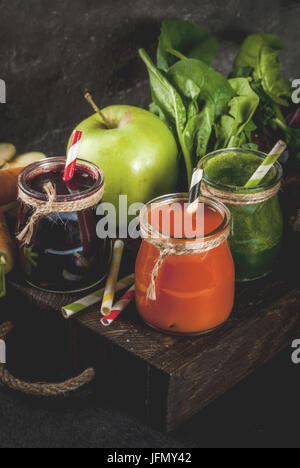 Vegan diet food. Detox drinks. Freshly squeezed juices and smoothies from vegetables: beets, carrots, spinach, cucumber, apple. On dark stone backgrou Stock Photo