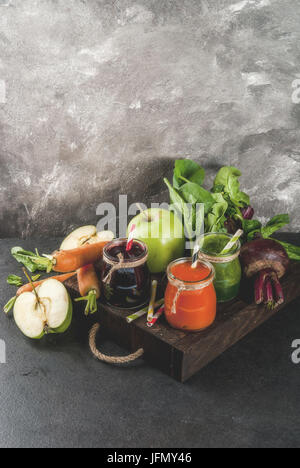 Vegan diet food. Detox drinks. Freshly squeezed juices and smoothies from vegetables: beets, carrots, spinach, cucumber, apple. On dark stone backgrou Stock Photo