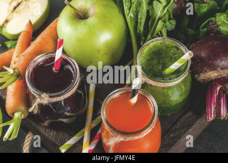 Vegan diet food. Detox drinks. Freshly squeezed juices and smoothies from vegetables: beets, carrots, spinach, cucumber, apple. On dark stone backgrou Stock Photo