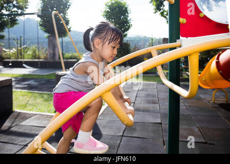 Asian Chinese little girl climbing stepladder at outdoor playground Stock Photo