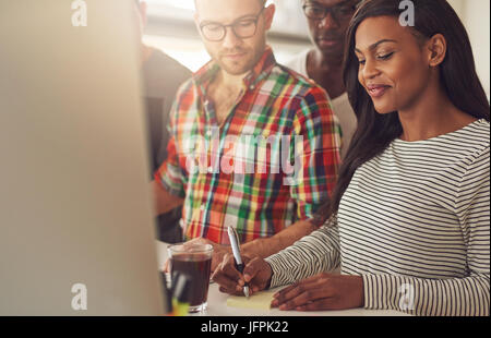 Young woman taking a note while the people looking at her in the office. Stock Photo