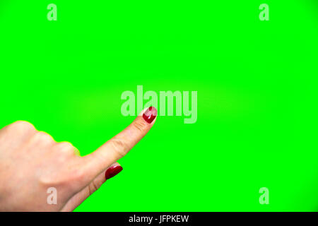 Young woman types and slides on a digital screen. Computer monitor with chroma key screen - green screen. Red nail polish fingers. Stock Photo