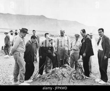 Ground Zero showing the melted remains of the atomic bomb tower after the first atomic test viewed by Dr. J. R. Oppenheimer, Director of Los Alamos Atomic Bomb Project and Physicist, (center with light hat)  and Maj General Leslie R. Groves (center), Chief of Manhattan Engineering District, . July, 1945. Alamogordo, NM, July 16, 1945 Stock Photo