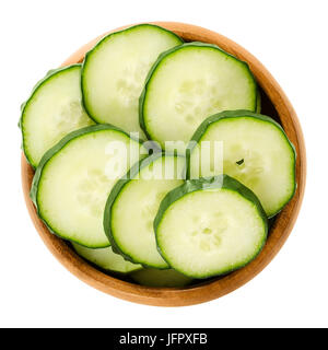 Cucumber slices in wooden bowl. Cucumis sativus. Sliced seedless vegetable, fresh and unripe with green skin. Isolated macro food photo close up. Stock Photo