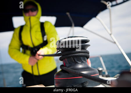 Sailor jacket pulls the rope winch on sailing yacht Stock Photo