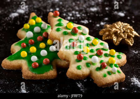 Christmas cookies and gingerbread in the form of fir - traditional food on dark background with sugar powder Stock Photo