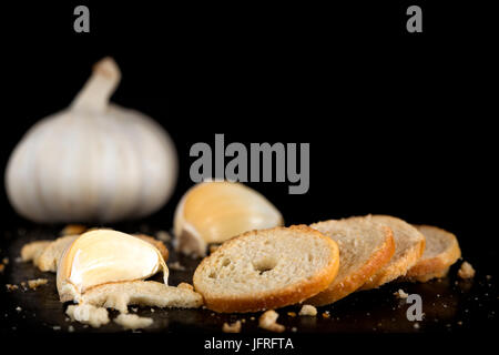 Mini rolls of baked bread and garlic on dark background Stock Photo