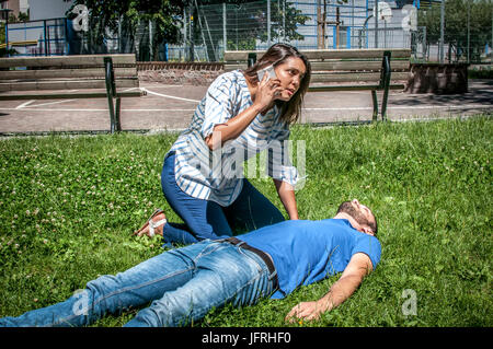 girl calling emergency service for an unconscious guy Stock Photo