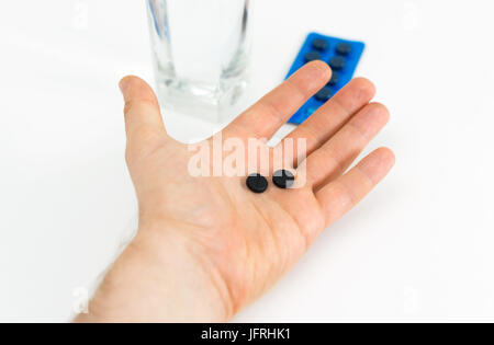 Man's hand holding activated carbon pills. Stock Photo