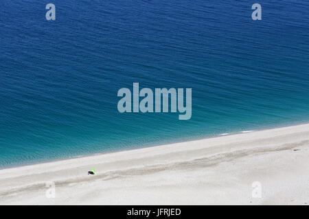 A green umbrella on a sandy beach in Cabo de Gata NP, Almeria, Spain. Stock Photo