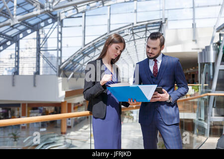 Business partners talking and looking at documents at business center Stock Photo