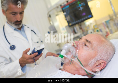 doctor near patient wearing oxygen mask in hospital room Stock Photo