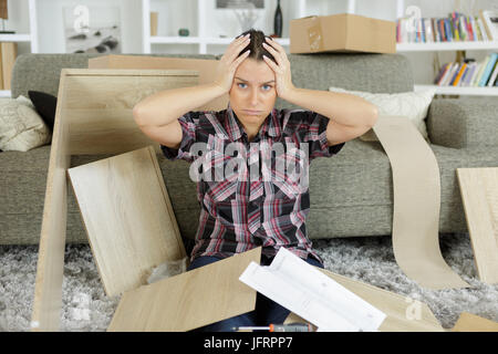 frustrated woman moving in new home trying to assemble table Stock Photo