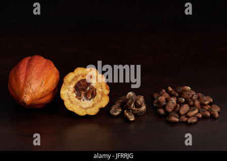 Different stages of cacao. Fruits, open cocoa pod and seeds on dark wooden background Stock Photo
