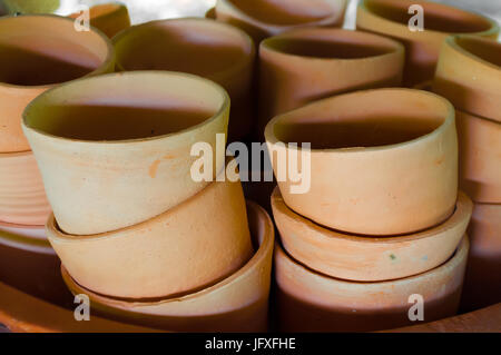 Pile of handmade baked clay cups waiting for glazing in pottery workshop. Stock Photo