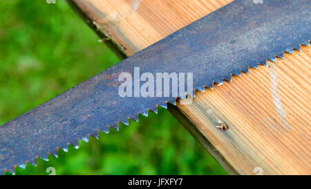 An old hacksaw lies on a wooden board Stock Photo