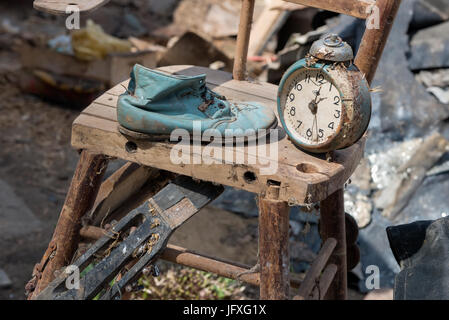 Old watches and a children's boot stand on an old broken highchair Stock Photo