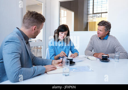 Young coworkers talking together in an office meeting room Stock Photo