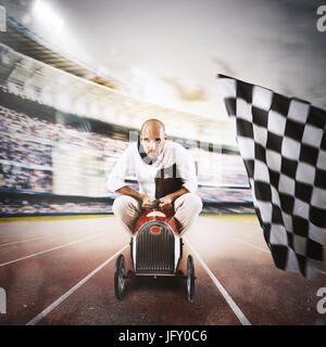 Successful businessman in a small car on the finishing line Stock Photo