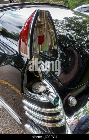 The gas cap on a classic 1948 Cadillac convertible is located under the left tail light and is accessed by pressing  a small blue button. Stock Photo