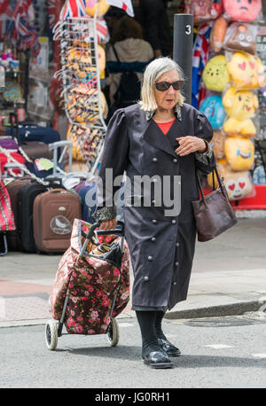 Elderly woman pulling a shopping trolley. Stock Photo