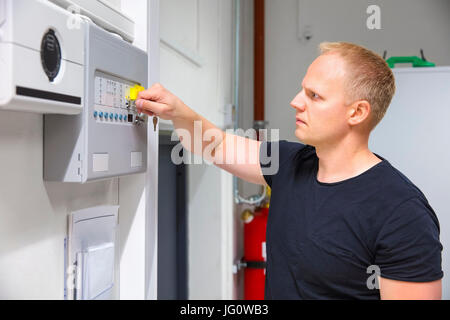 Confident mid adult male IT technician opening fire panel in server room Stock Photo