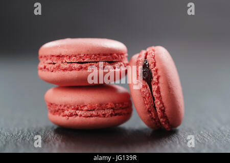 three raspberry macarons on slate board, closeup Stock Photo