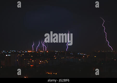 Photo of beautiful powerful lightning over big city, zipper and thunderstorm, abstract background, dark blue sky with bright electrical flash, thunder Stock Photo